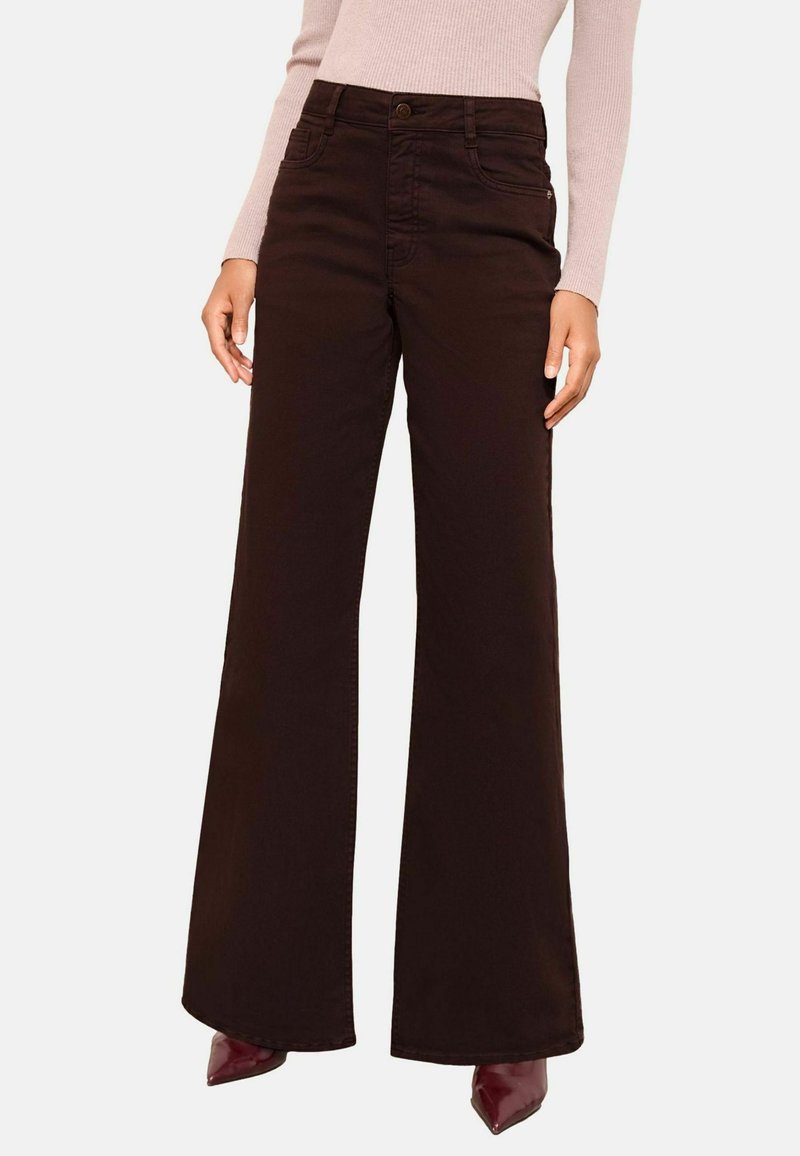 Smeđe široke hlače od denima s ušivenim detaljima, prednjim džepovima i dugmetom za zatvaranje. U kombinaciji su s laganom majicom i cipelama na špic.