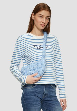 Sac à bandoulière en bleu clair, rembourré, en tissu tissé avec une finition texturée. Le modèle porte une chemise à rayures à manches longues avec "plus d'histoires d'amour" imprimé.