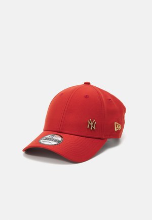 Gorra de béisbol roja hecha de tela con visera curvada. Presenta el logo dorado de los New York Yankees y acentos dorados adicionales en el lado.