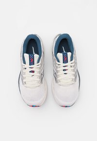 Scarpe da ginnastica bianche con una tomaia testurizzata, interno blu scuro e accenti colorati sulla linguetta e sulla suola. Design con lacci.