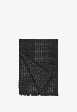 Coperta nera intrecciata con motivo a griglia bianca, con bordi frangiati e una texture morbida, piegata per mostrare lo strato interno.