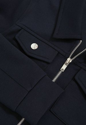 Námořnické svrškové s potahem, stříbrným zipem, detaily na druky a strukturovaným límcem s přední kapsou.