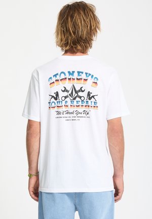 White cotton T-shirt with a colorful graphic on the back featuring "Stoney's Tow & Repair," tools, and silhouettes, in vibrant hues.
