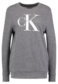 Sweatshirt gris en tissu doux avec un col rond. Affiche un grand logo "CK" blanc à l'avant et des poignets et un ourlet côtelés.