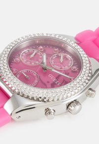 Lyserød gummiremur med en sølvbezel pyntet med krystaller. Har en lyserød urskive med tre sub-dials og sølv time markeringer.