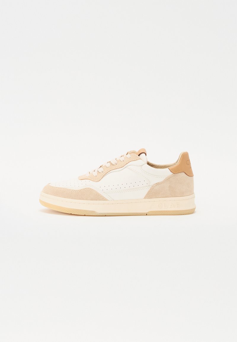 Weiße und beige Sneaker aus Leder und Wildleder. Merkmale sind Perforationen, runde Schnürsenkel und eine strukturierte Gummisohle mit Branding an der Ferse.