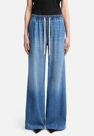 Pantaloni in denim leggeri di colore azzurro, a gamba larga, con vita elastica, dettagli con cordoncino e una leggera texture sbiadita. Cuciture piatte all'orlo.