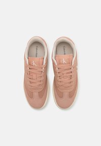 Sneakers rosa con una toma superiore in materiale sintetico liscio, pannelli in rete testurizzata e lacci piatti. Logo sul lato, fodera interna crema e suola in gomma.