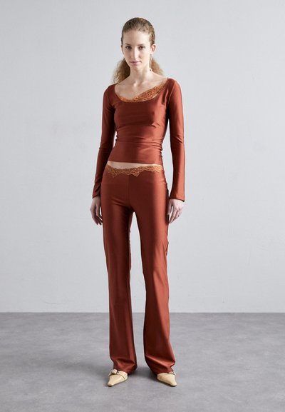 Top a maniche lunghe color ruggine con bordo in pizzo, abbinato a pantaloni attillati. Tessuto morbido ed elastico; alta vita con dettagli in pizzo.