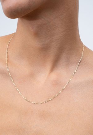 Gold chain necklace with elongated links and circular accents, resting on bare skin, featuring a smooth, polished finish.
