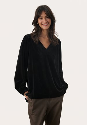 Black velvet top with a V-neck and long puffed sleeves, featuring a loose fit and gathered cuffs. Paired with brown trousers.