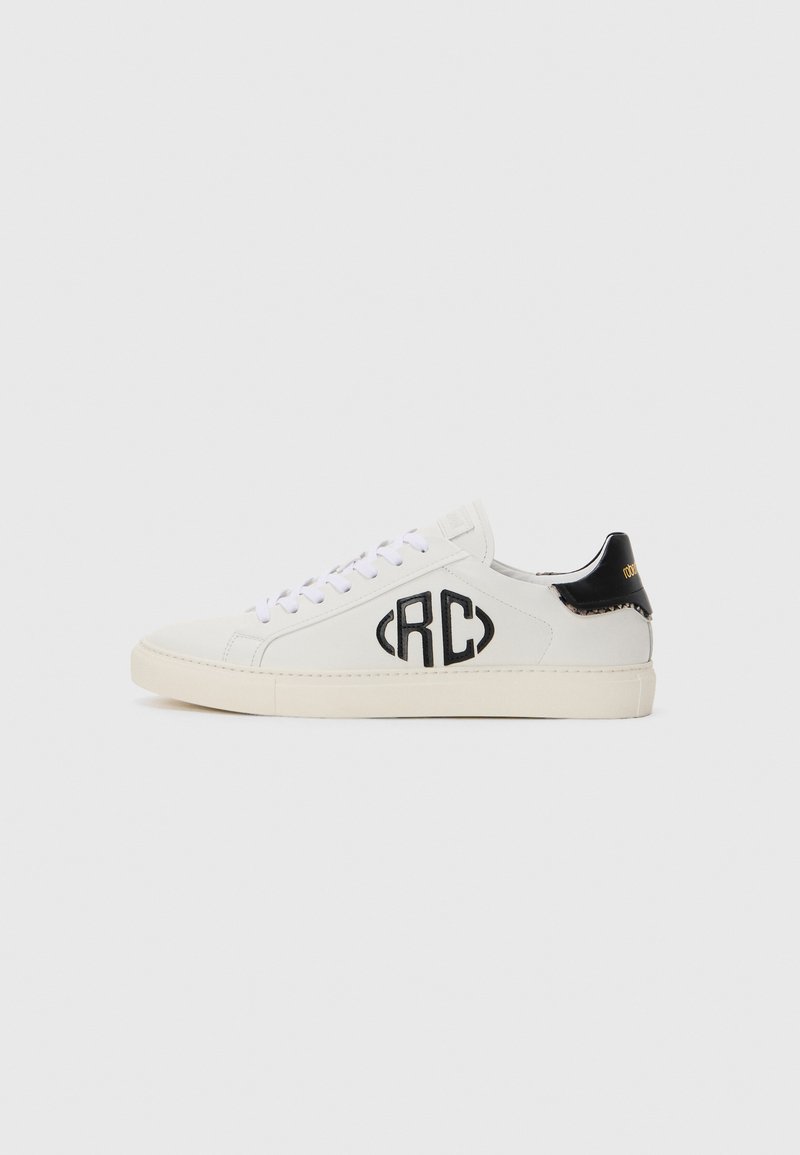 White low-top sneaker with black "RC" logo on the side and black heel tab with gold text, displayed against a plain light background.