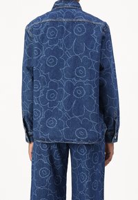 Jeansowa kurtka z dużym kwiatowym wzorem w jasnoniebieskim kolorze na ciemnoniebieskim tle. Posiada wywijany kołnierz i mankiety zapinane na guziki.