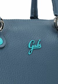 Bolso de cuero azul texturizado con herrajes plateados y un logo turquesa. Presenta costuras visibles y un diseño elegante y minimalista.