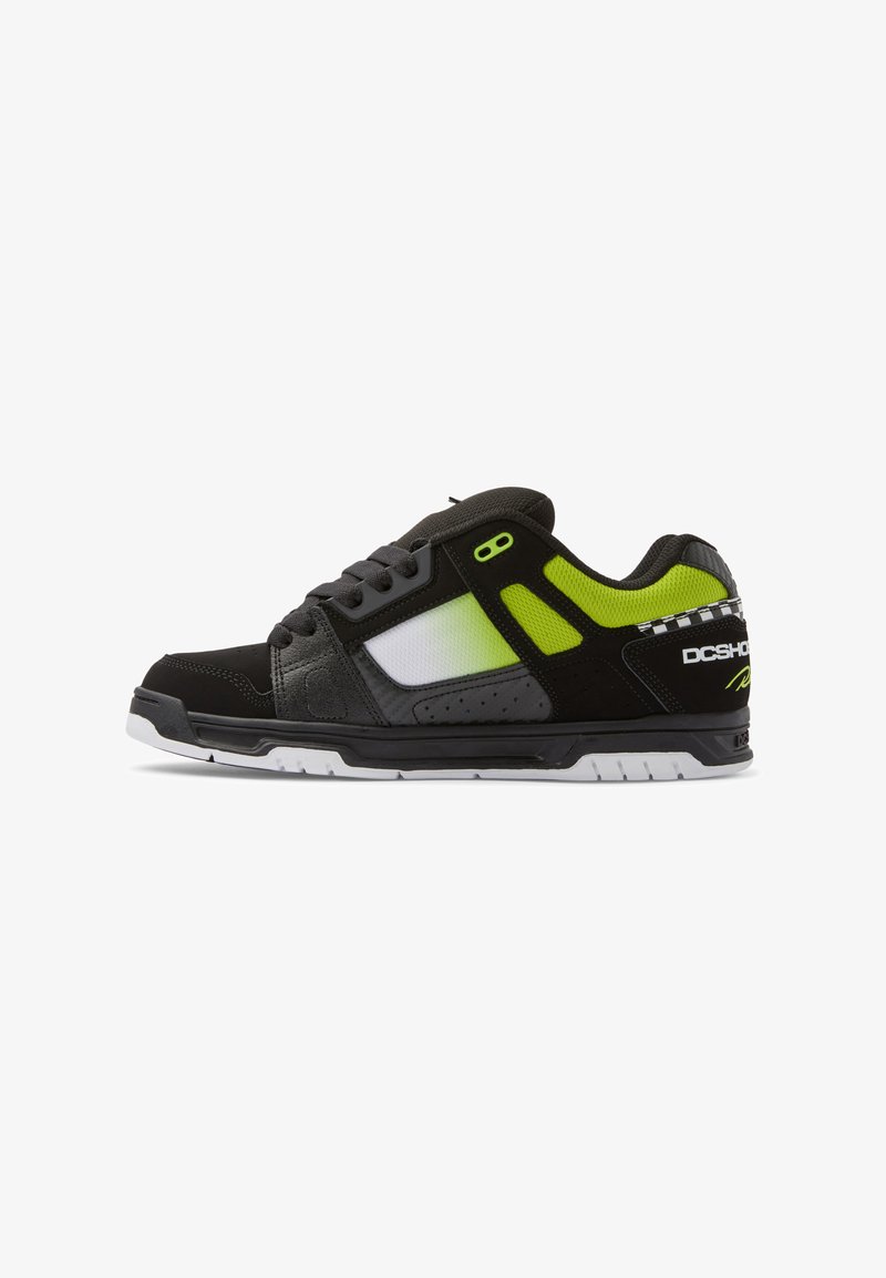 Black and gray sneaker with neon green accents; features a mix of materials, including mesh and leather, with a white rubber sole and branding.