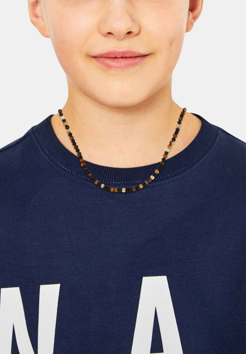 Perlenkette mit kleinen, mehrfarbigen Perlen in Schwarz, Braun und Grau, getragen über einem dunkelblauen Sweatshirt mit weißem Text.