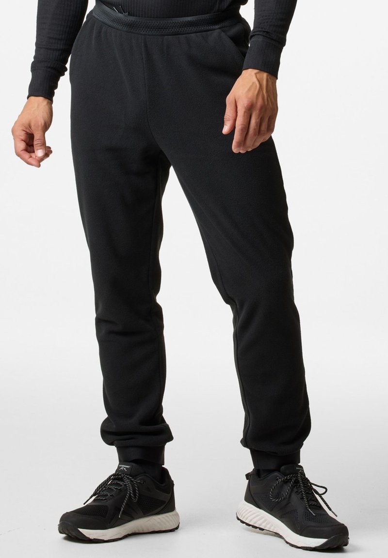 Zwarte fleece joggerbroeken met een aansluitende tailleband, taps toelopende broekspijpen en een gladde textuur. Draagt zwarte sportschoenen.
