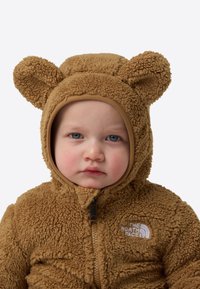 Hanorac pentru bebeluși cu fermoar, din fleece maro, cu urechi de urs, model texturat și glugă elastică; prezintă logo-ul The North Face pe piept.