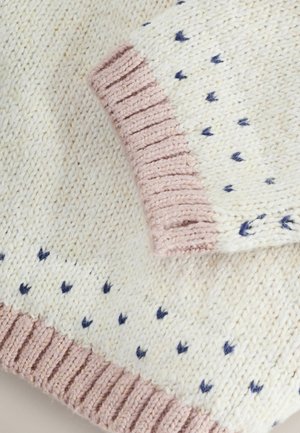 Pleteni pulover v kremenčevi barvi z majhnimi temno modrimi vzorci src, s svetlo roza rebrastim manšetom za teksturo in kontrast.