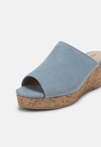 Sandales compensées bleu clair à bout ouvert avec une tige en suède lisse et une plateforme en liège texturée. Coutures remarquables le long du bord de la tige.