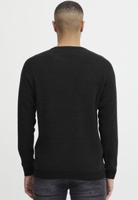 Svart strikket genser med teksturert finish, ribbede mansjetter og nederkant. Designet har rund hals og lange ermer.