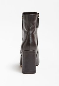 Botas de tobillo de cuero negro con punta redondeada, acabado suave y tacón robusto. Cuenta con un zipper lateral y detalles de costura mínimos.