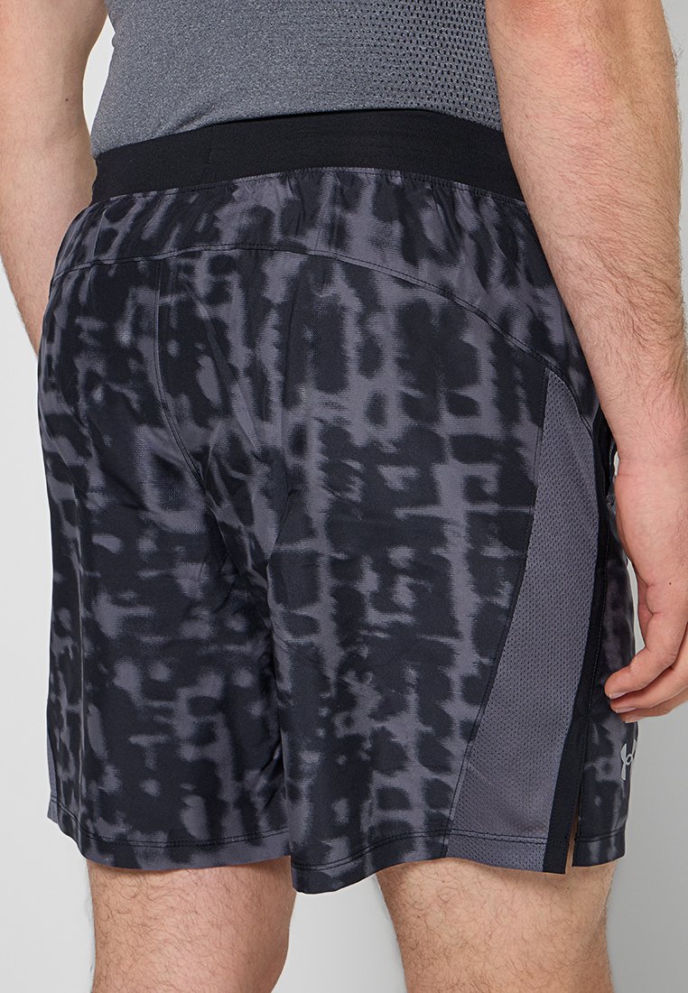 Homme portant un short de sport noir et gris à motifs avec des panneaux en maille sur les côtés et une taille élastique noire.