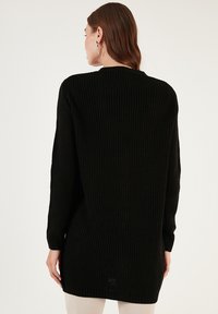 Fekete kötött overméretű pulóver, bordázott textúrával, hosszú ujjakkal, kerek nyakkivágással, csípő alá érő, egyenes szegéllyel.