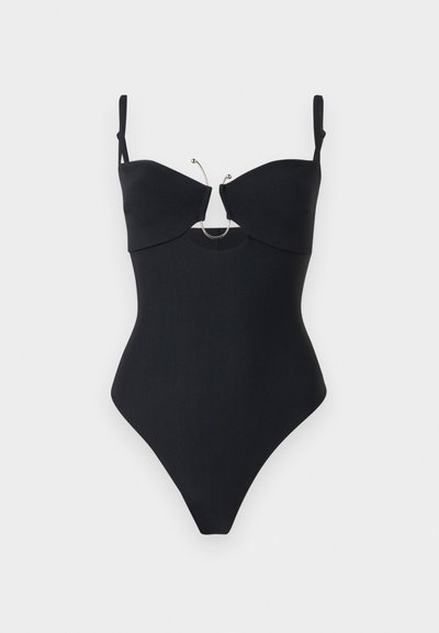 Maillot de bain une pièce noir à côtes avec bretelles ajustables, ouverture sous la poitrine et anneau décoratif argenté au centre.