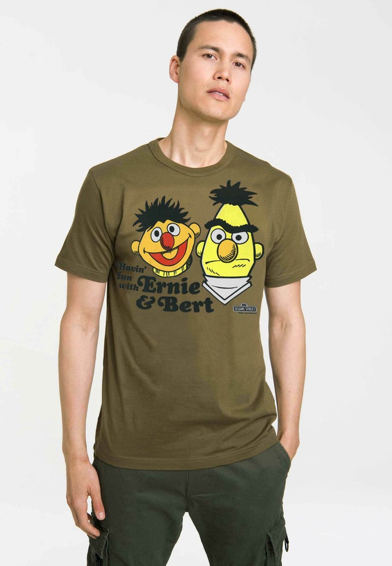Olive green cotton t-shirt featuring a graphic print of two cartoon characters with vibrant colors, round faces, and playful expressions.