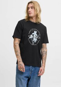 Sort bomulds t-shirt med et centralt blomstermotiv i hvid, normal pasform, med korte ærmer og rund halsudskæring, parret med blå jeans.