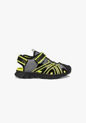 Sandales de sport avec un design noir et gris, des accents jaunes, une tige en mesh, des sangles ajustables et une semelle en caoutchouc texturée.