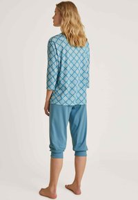 Blauw gemusterd lang mouwtop met driekwart mouwen, gecombineerd met effen blauwe cropped broek. Zachte textuur, ontspannen pasvorm en casual stijl.