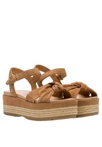 Hnědé semišové platformové sandály s kříženými popruhy a uzlem v přední části. Obsahují tkaný přírodní provazový akcent kolem spodní části.