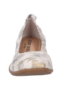 Zapato plano con un upper blanco estampado que presenta acentos en gris y dorado, con punta redondeada y suela de goma beige. Interior forrado con la marca visible.