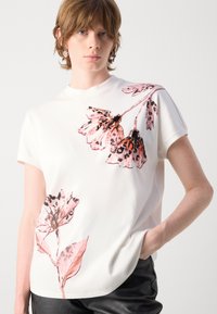 Witte korte mouwen t-shirt met een grote bloemenprint in roze en zwart op de voorkant. Glad materiaal en een casual pasvorm.