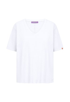Biała koszulka z krótkim rękawem i dekoltem w serek, z fioletową metką marki wewnątrz kołnierza oraz małą pomarańczową metką na lewym rękawie.