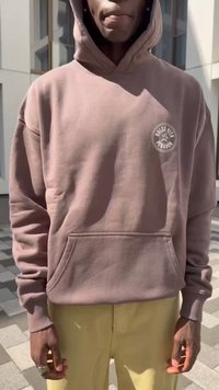 Rjava kapuca z sprednjim žepom in krožno grafiko na levi prsni strani. Mehka tkanina z rahlo ohlapnim krojem. V kombinaciji z rumenimi hlačami.