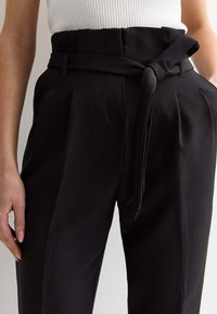 Zwarte high-waisted broeken met een riemdetail, voorzien van plooien en zijzakken, gemaakt van een soepel stof voor een op maat gemaakte uitstraling.