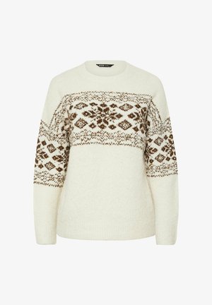 Kermainen neulepaita, jossa on ruskeita geometrisia ja kukkakuoseja rinnassa ja hihoissa. Paita on pyöreäkauluksinen ja pitkähiha.