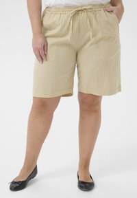 Shorts rayés beiges en tissu léger avec une taille élastique et un cordon de serrage, comportant des poches de chaque côté.