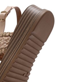 Sandalo platform marrone con upper in paglia intrecciata e dettagli dorati, suola in gomma testurizzata con scanalature e cinturino alla caviglia regolabile color beige.