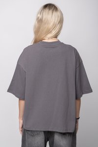 Šedé oversized tričko s krátkým rukávem, kulatým výstřihem, měkkým bavlněným materiálem a jemnou texturou. Obsahuje uvolněný střih a minimální šicí detaily.