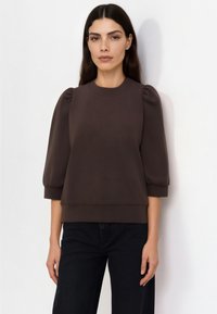 Felpa marrone con collo rotondo a coste, maniche arricciate e vestibilità morbida. Realizzata in tessuto morbido, con una texture liscia.