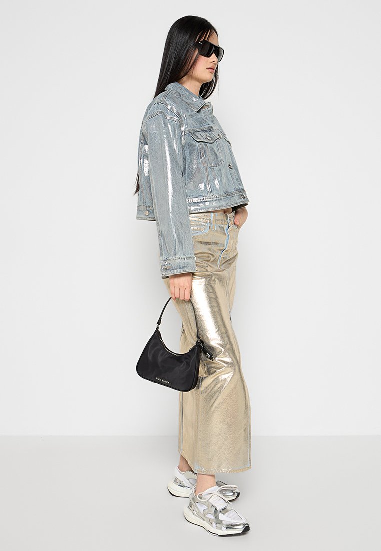 Veste en denim avec une finition brillante, pantalon large métallique doré, sac à main noir et chaussures de sport argentées avec des détails en mesh.