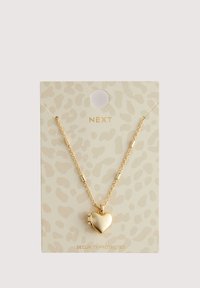 Gold heart pendant necklace on a beige leopard print card. The chain has cylindrical accents and a secure attachment for the pendant.