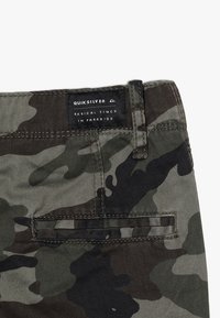 Shorts van camouflagepatroon in tinten groen, bruin en zwart; met een gestikte achterzak en een merklabel aan de taille.