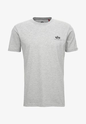 Jasnoszara koszulka z krótkim rękawem i okrągłym dekoltem, z małym czarnym logo Alpha Industries na lewej piersi.