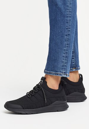 Black athletic shoes made of breathable knit material, featuring textured detailing, flexible soles, and contrasting patterned laces.