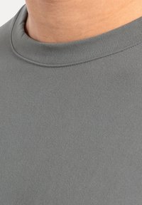 Camisa gris de manga corta con cuello redondo, hecha de una tela suave, que presenta costuras finas en el cuello y las mangas.